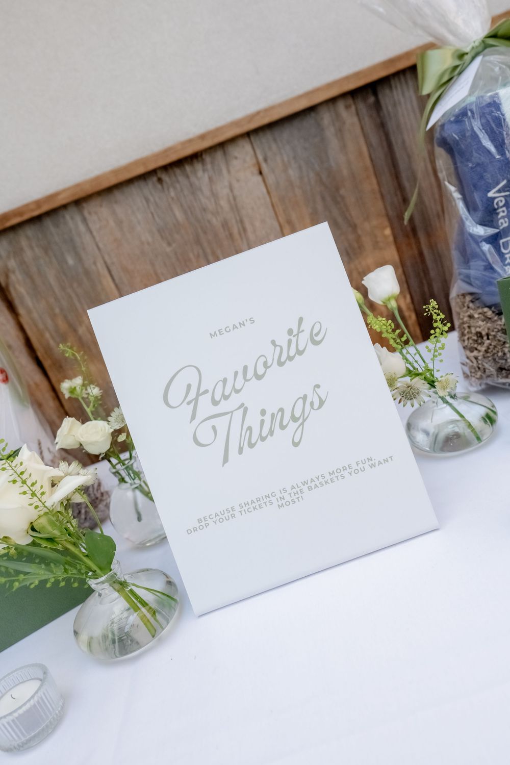 Elegant wedding sign reading Megan's Favorite Things displayed on white table with floral arrangements and candles.