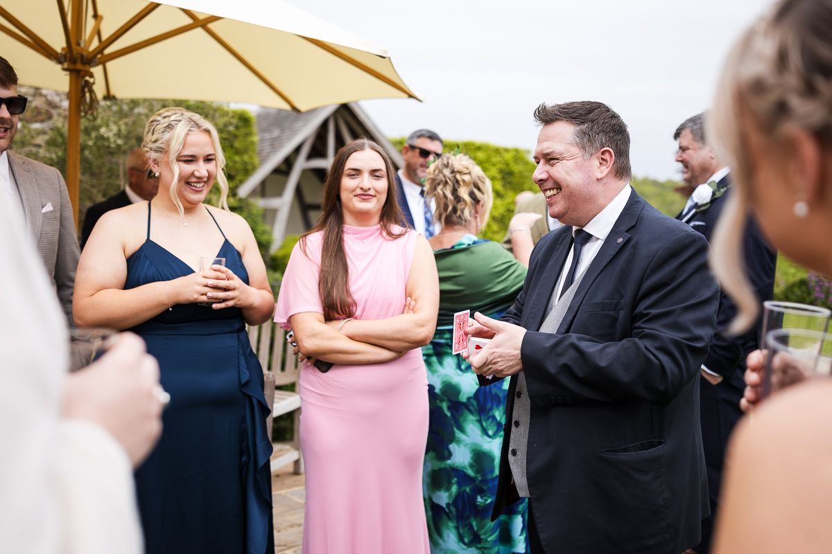 Guests laughing and socializing at an outdoor wedding reception, dressed in formal attire including navy and pink dresses.