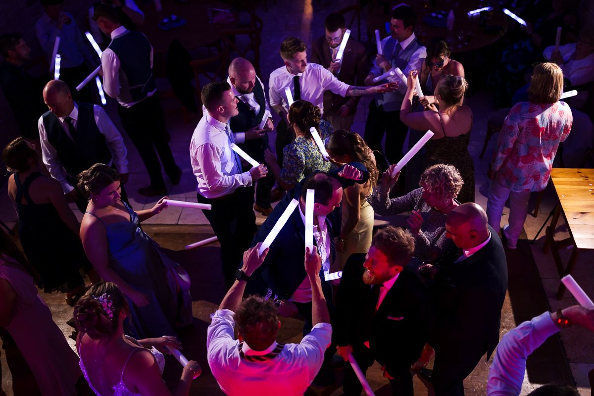 Aerial view of people dancing at a nightclub event with purple and pink lighting illuminating the crowd from above.
