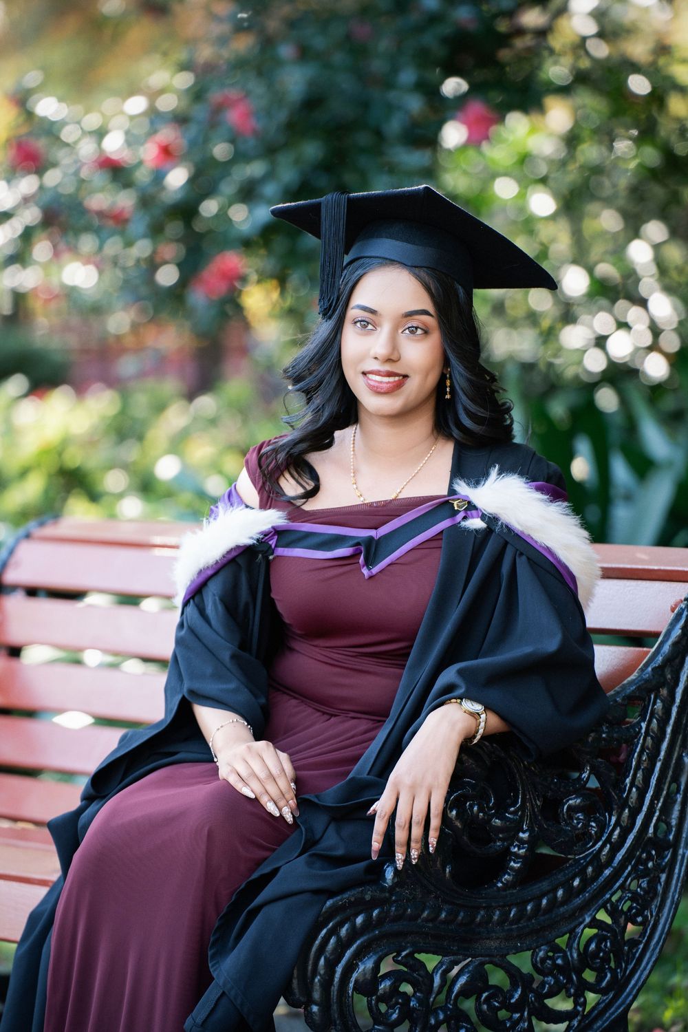 Portrait of a smiling graduate sitting on a park bench in Auckland Domain for her graduation photography.