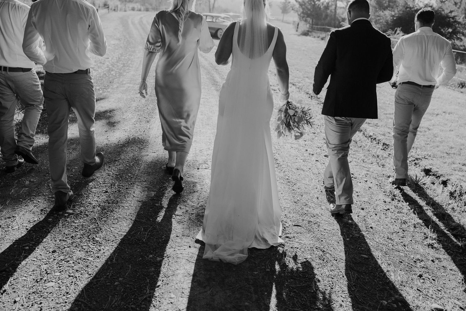 Black and white, wedding party confidently walking away into the afternoon sun.