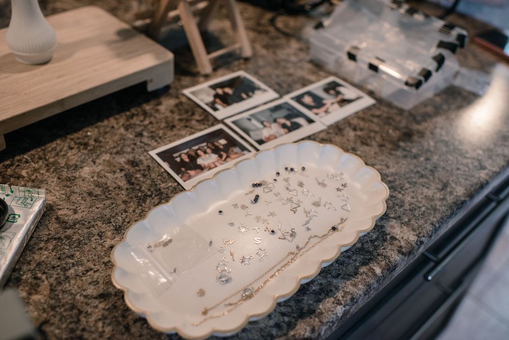 White oval ceramic platter on granite countertop beside vintage Polaroid photos and jewelry organizer.