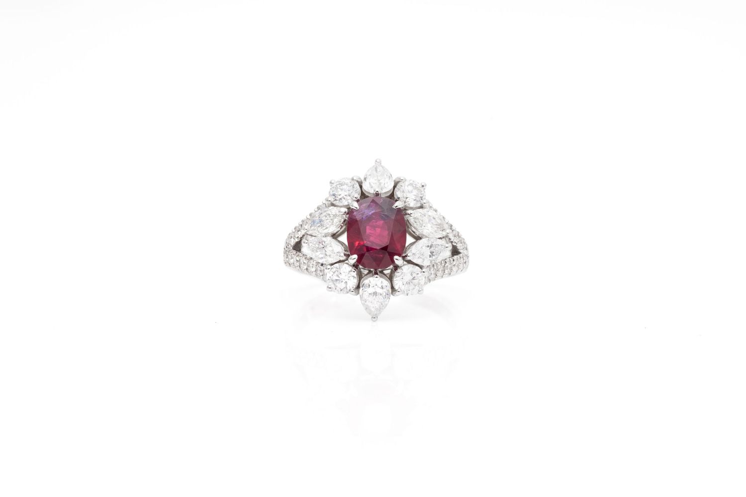 Elegant ruby and diamond halo cocktail ring set in white gold on a white background.