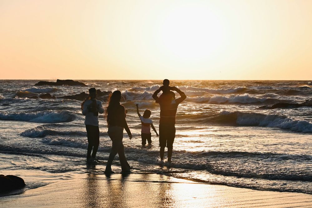 Silhouette of a family with children enjoying a golden sunset on a sandy beach.