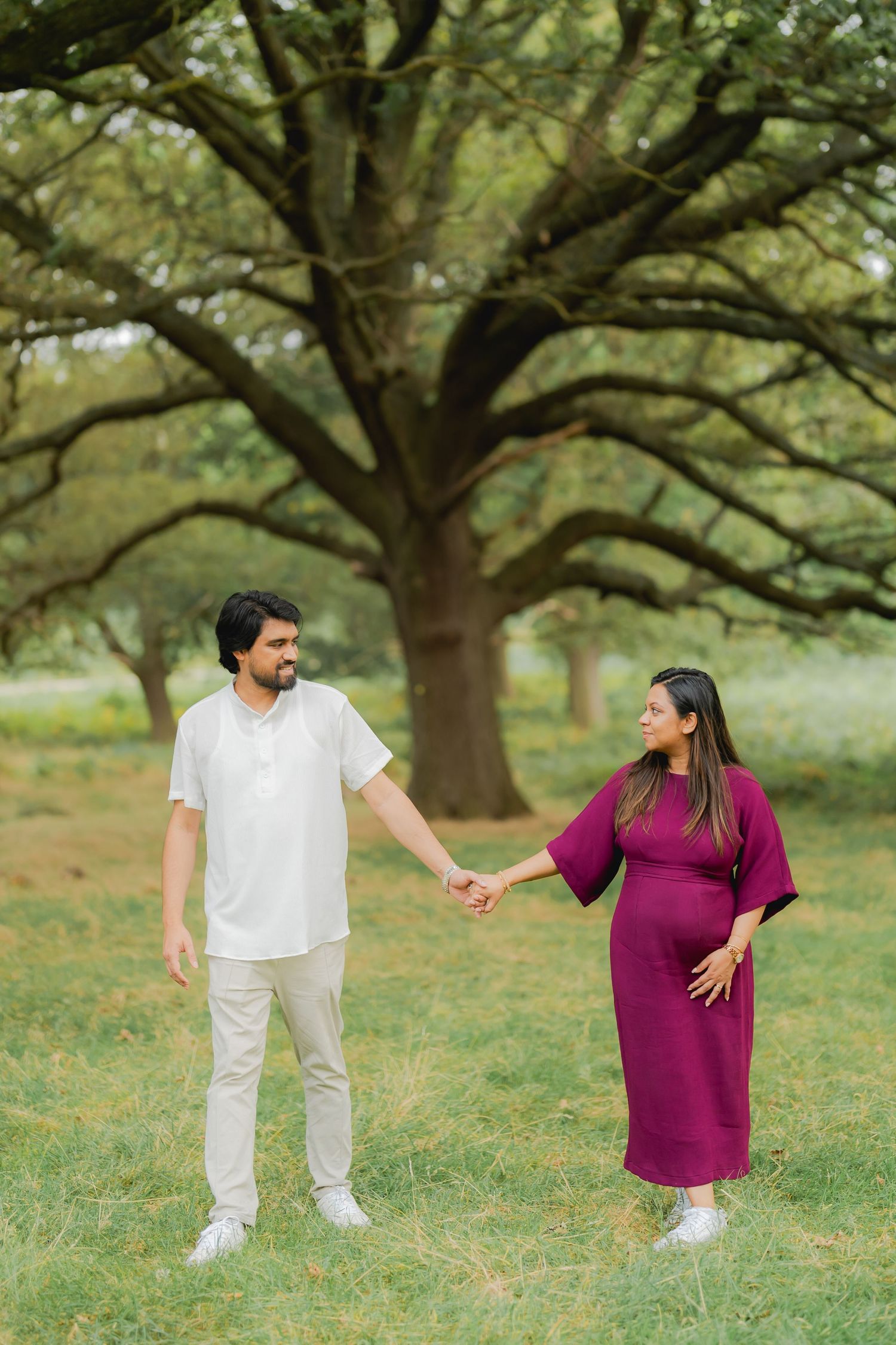 Indian couple walking together, bride in red saree and groom in black suit.