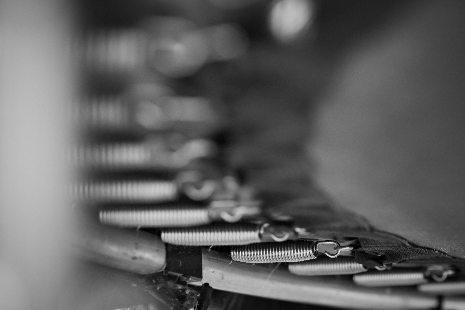 Close-up black and white photo of vintage typewriter keys and springs in a row, showcasing intricate mechanical details.