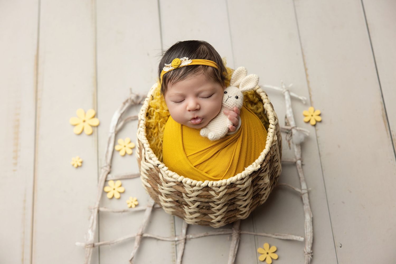 Newborn baby in teal hooded knit onesie with wooden buttons, sitting in a vintage metal bucket with soft teal blankets.