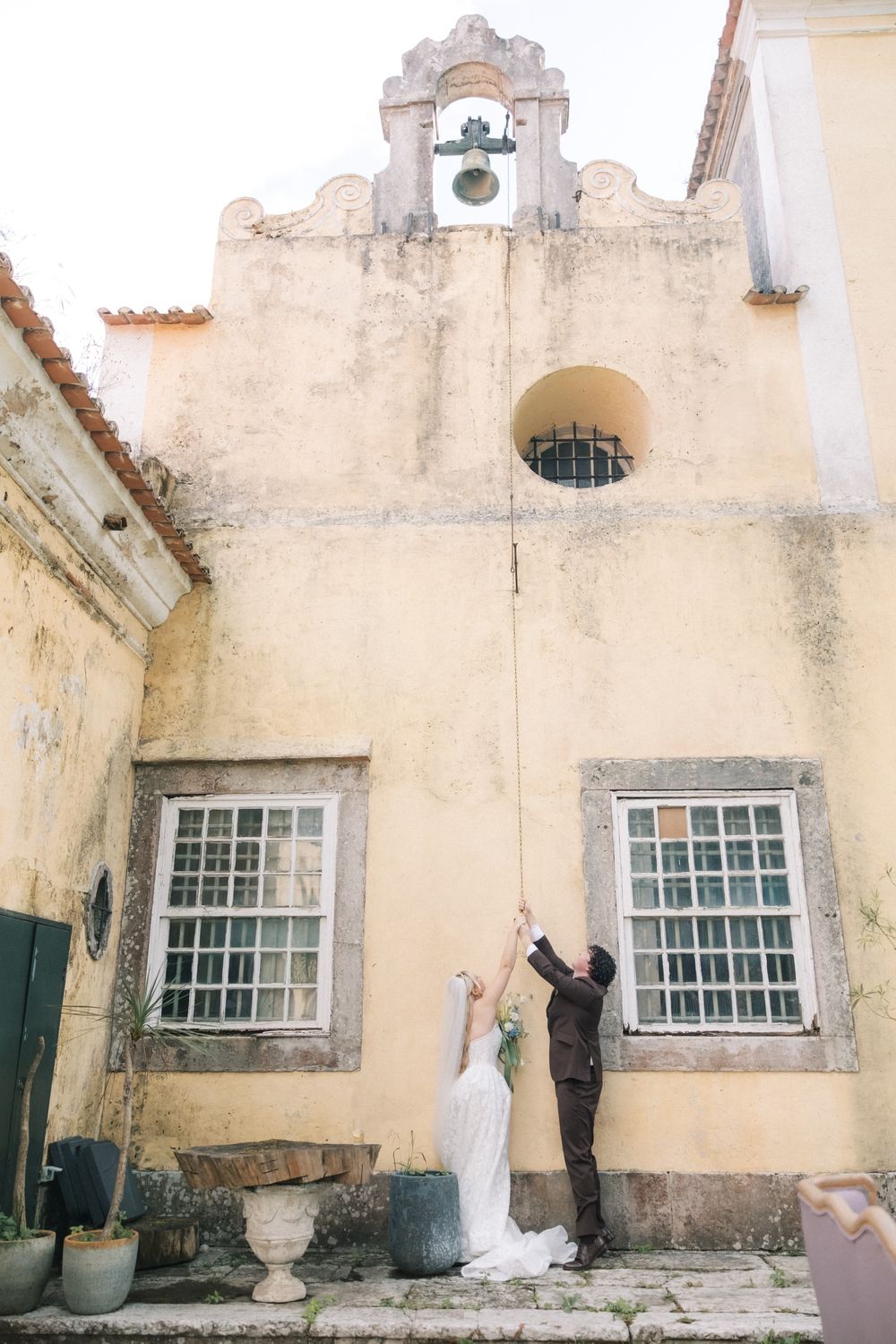 Newlyweds celebrating beneath the bell tower at Quinta do Torneiro