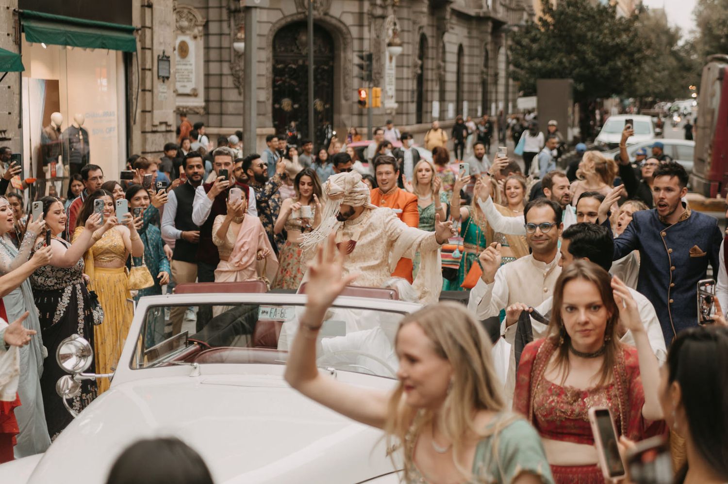 Joyful Indian wedding baraat procession with guests in colorful attire celebrating on a festive street.