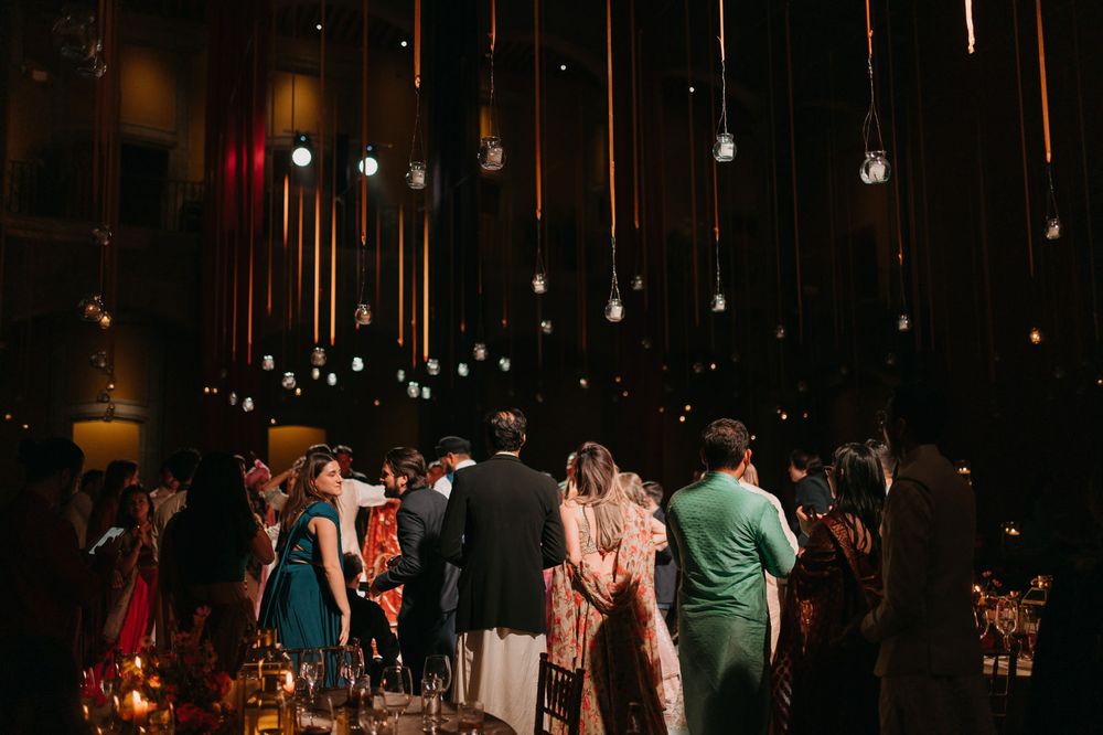 Guests mingle under hanging Edison bulb lights at an elegant indoor wedding reception.