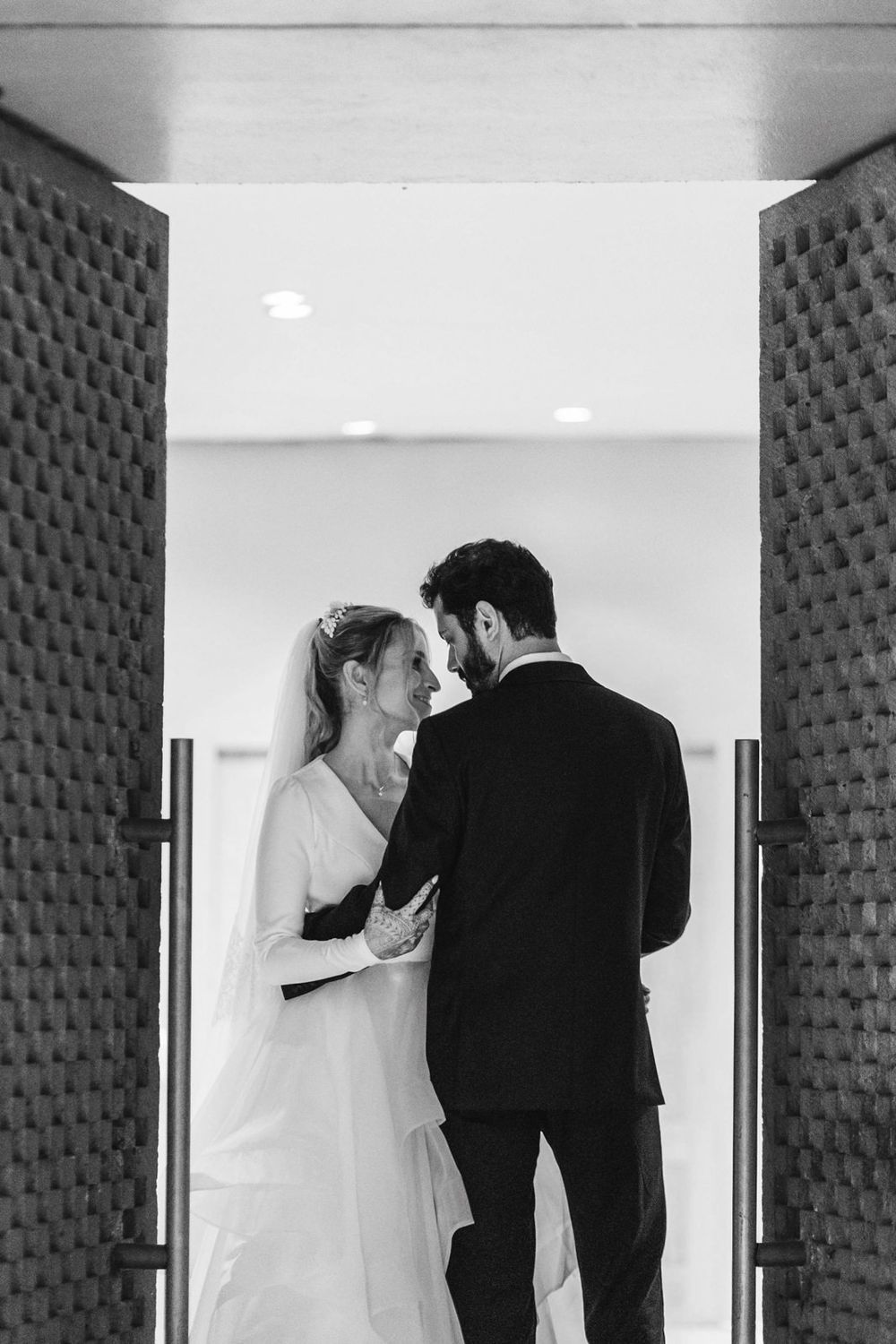 Black and white photo of a bride and groom sharing an intimate moment in a doorway on their wedding day.