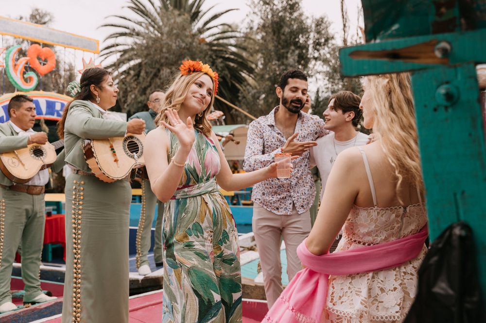 People dancing and celebrating at a festive outdoor party with mariachi band playing in background.