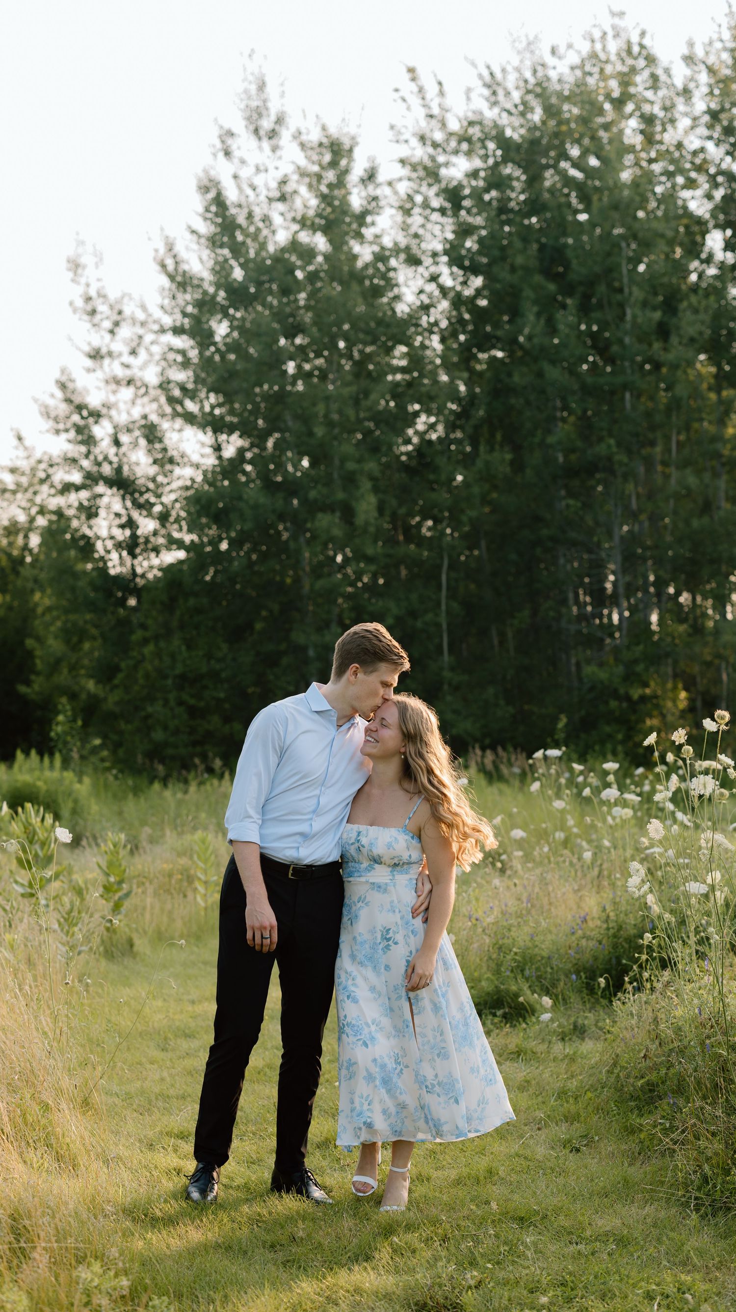 Couple embracing in a sunlit autumn forest with golden yellow leaves on trees and ground.