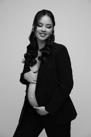 Black and white professional studio maternity portrait in business attire.
