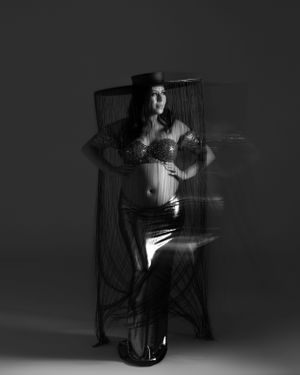 Artistic black and white portrait with figure behind sheer fabric screen.