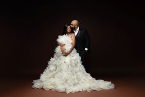 Elegant couple's maternity portrait in formal attire with flowing white gown.