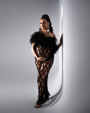 Full-length fashion portrait with feathered dress and curved light element.
