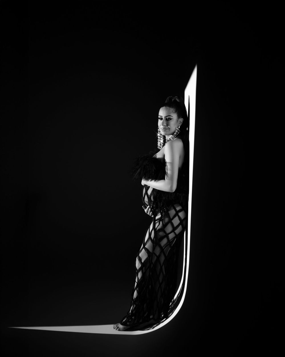 Dramatic monochrome fashion photo with curved light design and textured dress.