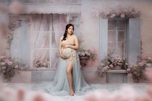 Ethereal maternity portrait in a soft blue gown with pink floral accents.