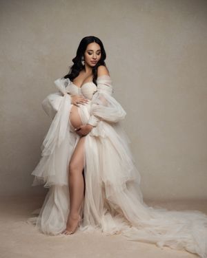 Romantic maternity portrait in ivory tulle gown with flowing layers.
