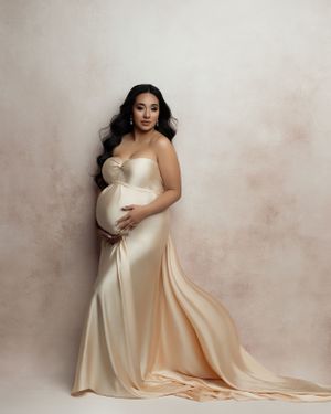 Classic studio maternity portrait in cream silk gown with flowing train.