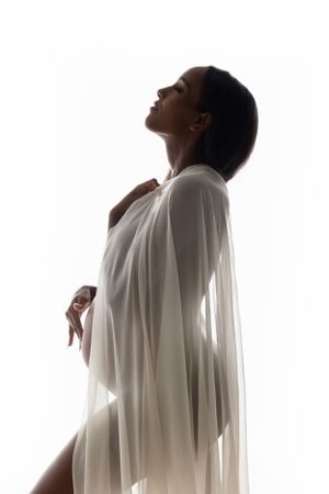 Minimalist silhouette maternity portrait with flowing white fabric.