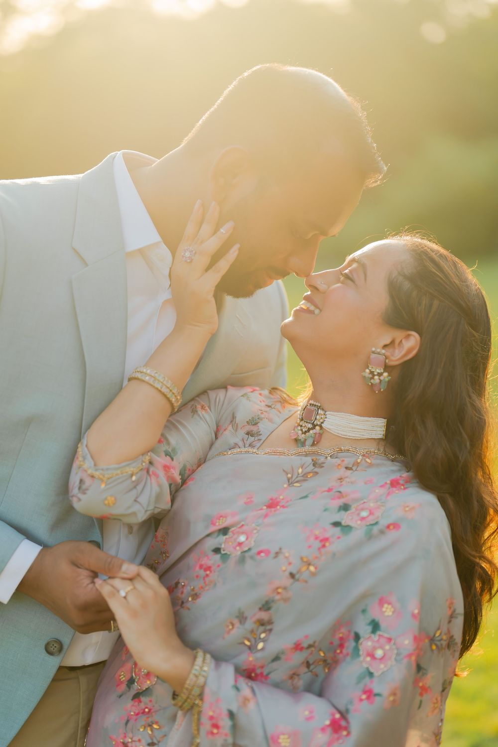 Couple in Indian attire sharing a romantic moment outdoors, bathed in golden sunset light.
