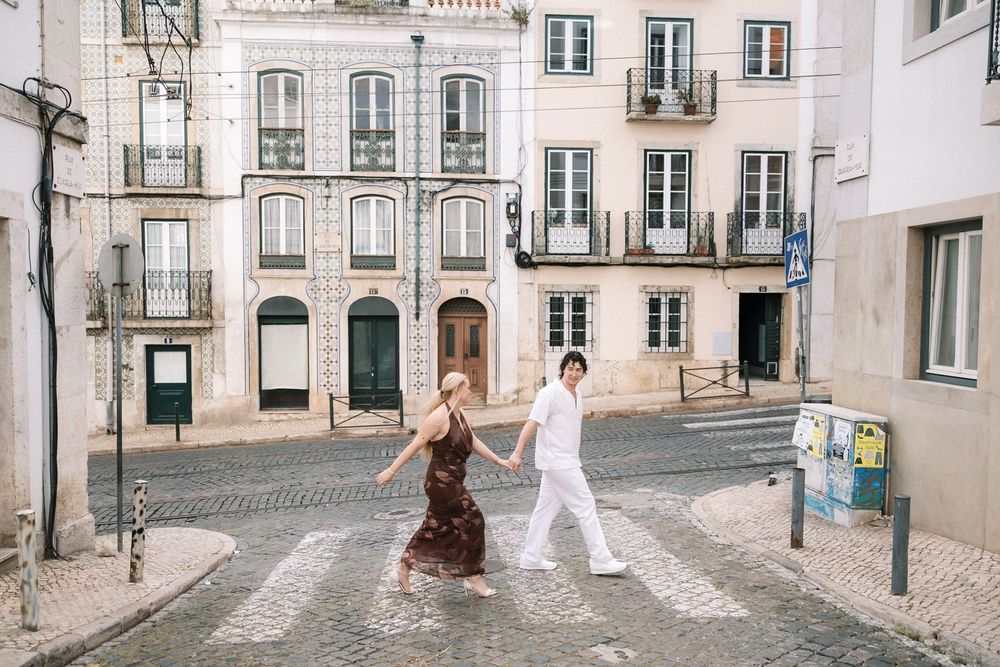 Destination wedding couple walking through historic Lisbon streets at sunset