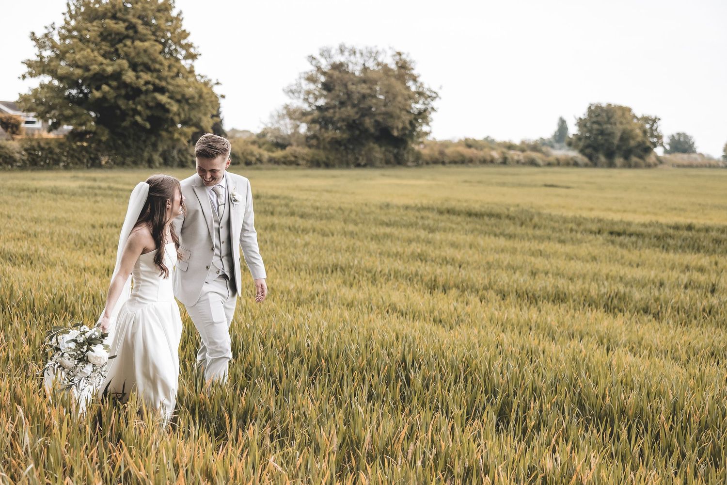 Unobtrusive wedding photo of newly weds walking together in a field at Beverley Barn