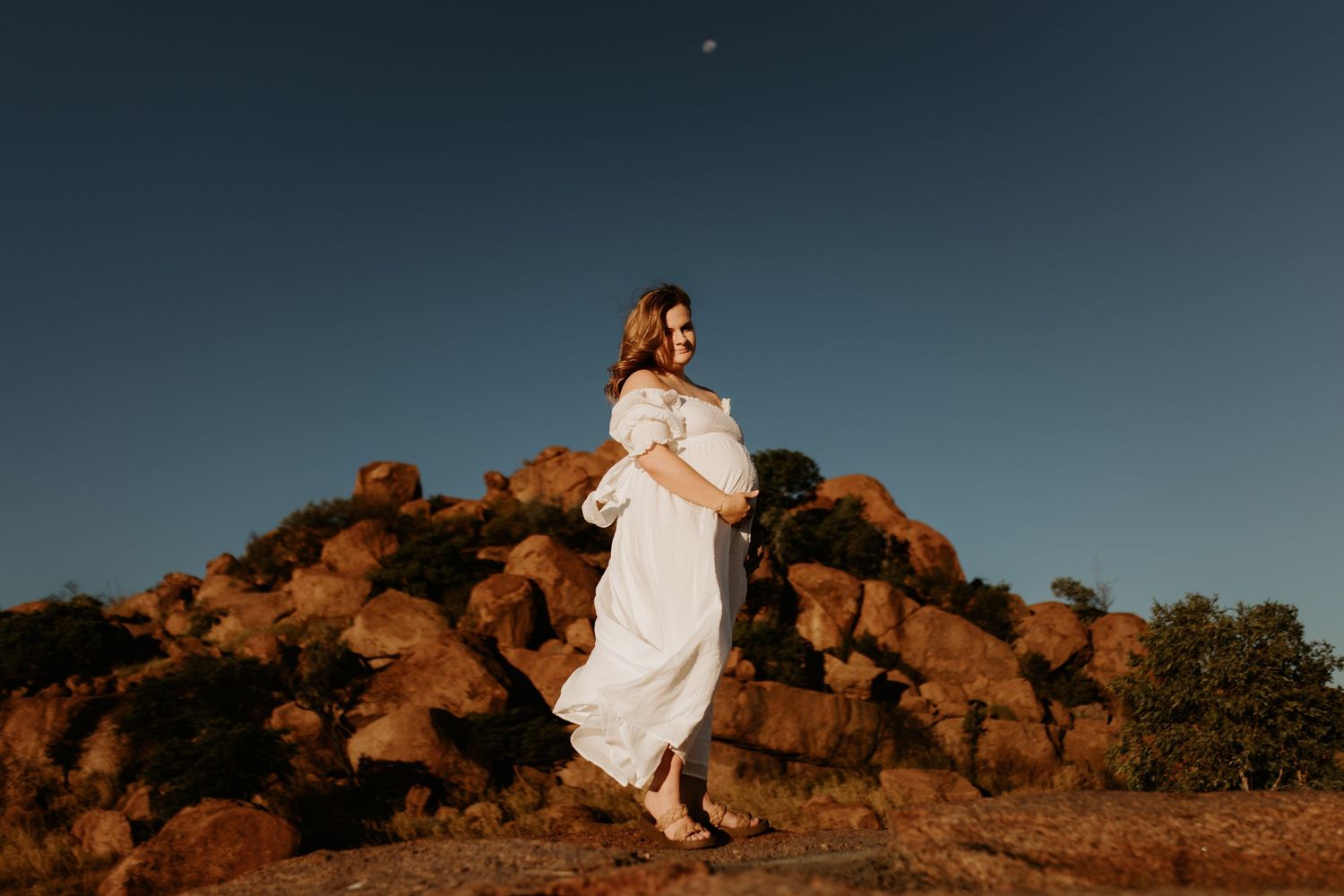 Pregnant woman standing in front of the red rock at Granite Mines in Mount Isa