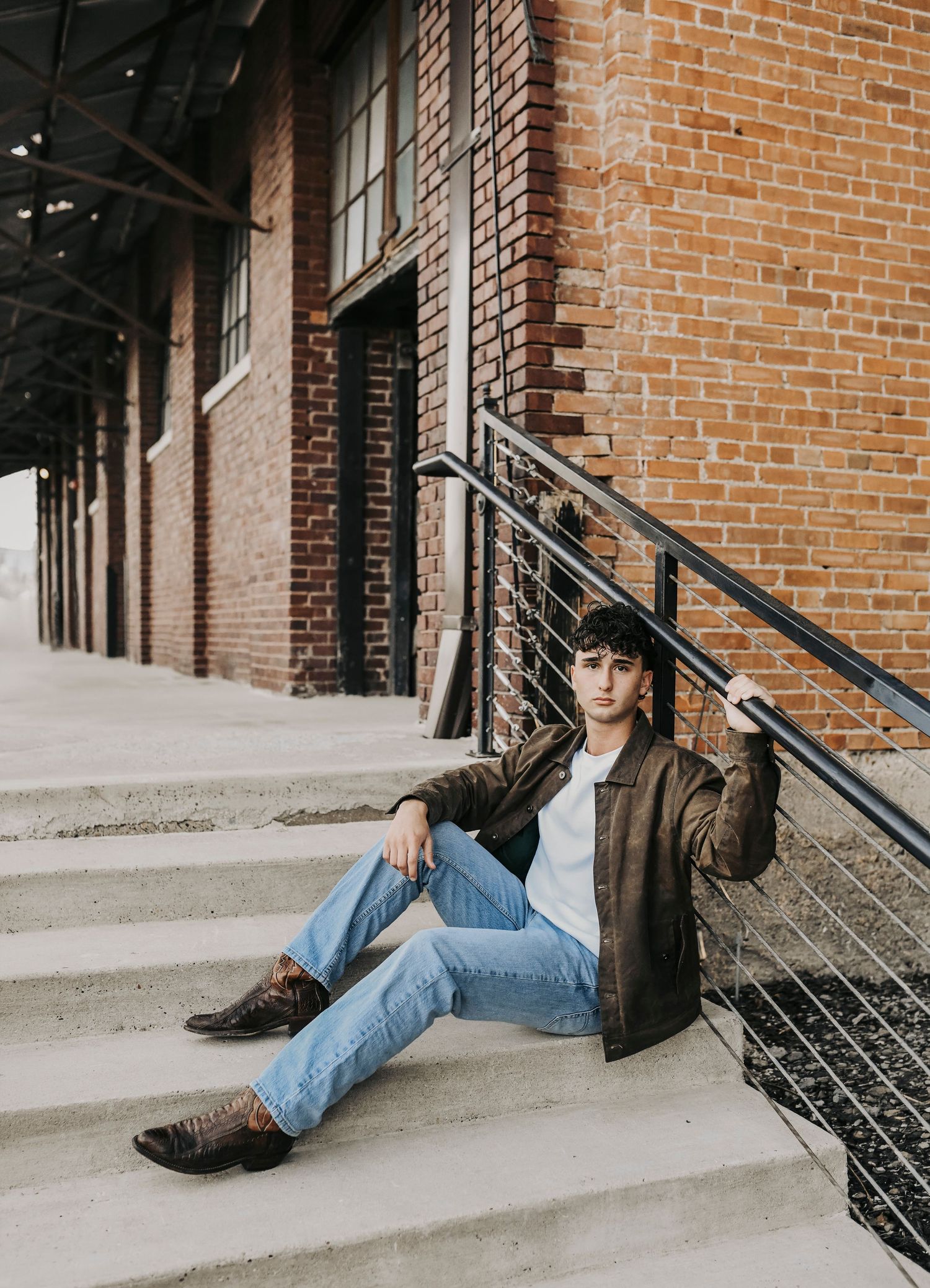 Senior photo session in McKinney Texas with rustic industrial backdrop and layered jacket styling