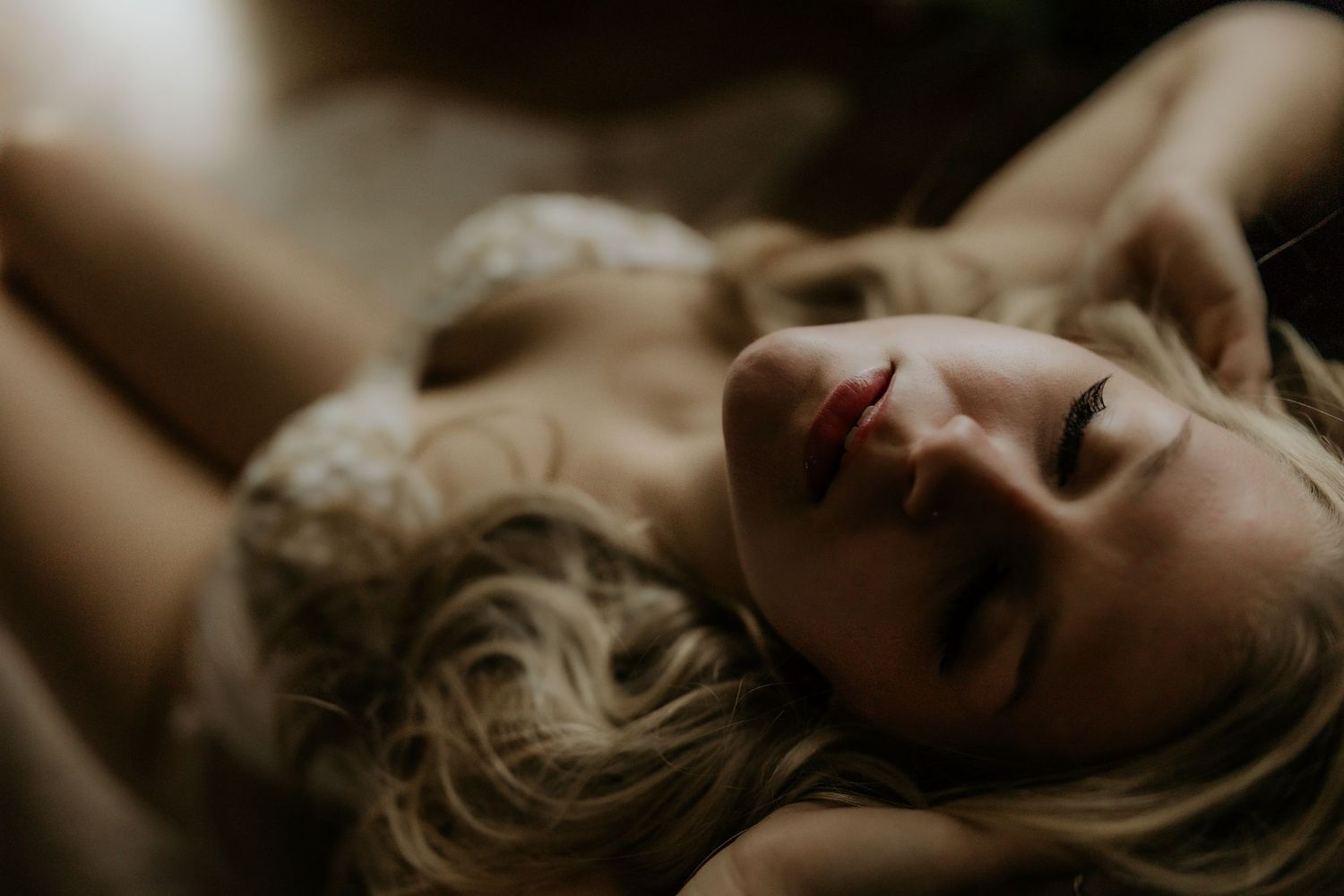 Artistic boudoir photography series in sepia tones showing intimate poses against dark backdrop.