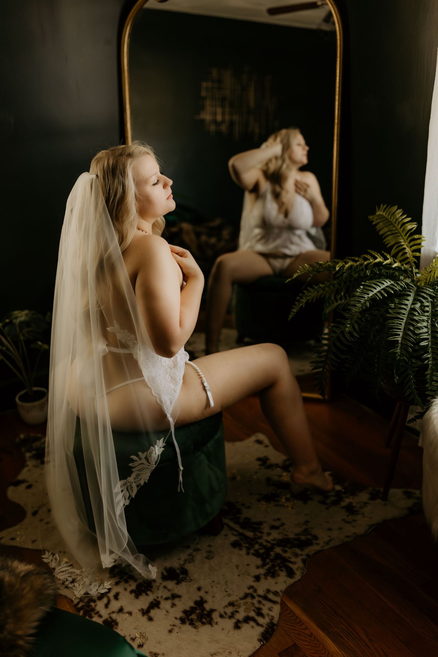 Artistic boudoir photography with soft lighting and fern shadows in a dark room.
