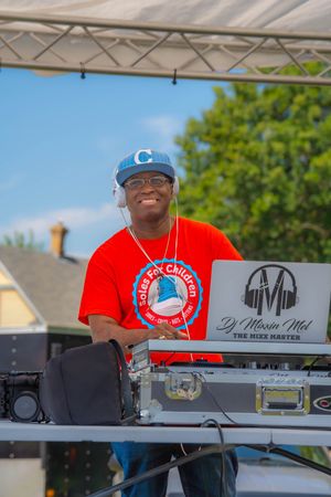 DJ performing at an outdoor event with professional mixing equipment and turntables on a sunny summer day. Quad Cities Photography