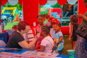Children participate in activities at a festive outdoor event with red decorations and tables. Quad Cities Photography