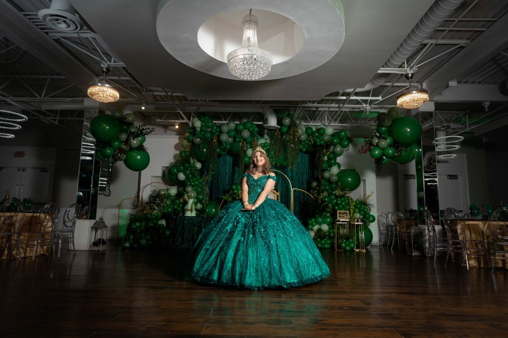 Elegant ballroom setting decorated with green balloons and crystal chandelier.