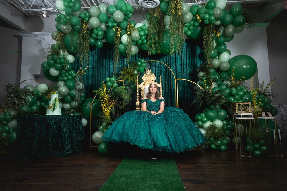 Elegant emerald green and gold themed party setup with balloon garlands and ornate decorations.