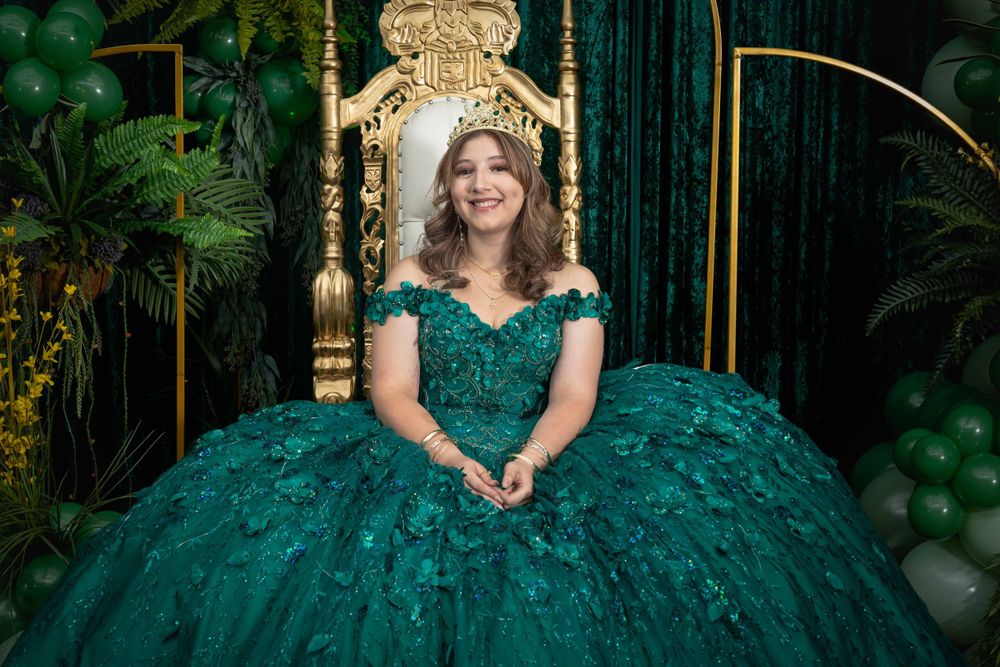 Stunning emerald green ballgown against a luxurious backdrop with gold accents and green balloons.
