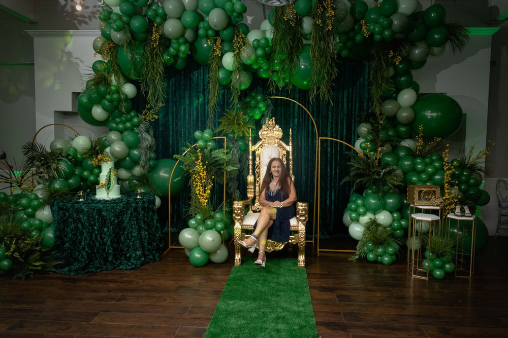 Luxurious party venue decorated with emerald green balloon arrangements and gold accents.