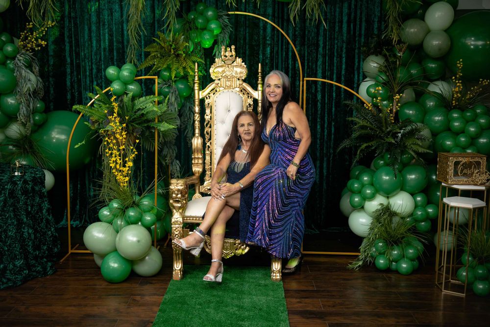 Celebration gathering with emerald green decor and elegant gold throne setting.