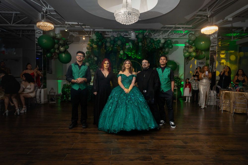 Spacious event venue decorated in emerald green with dramatic lighting and balloon arrangements.