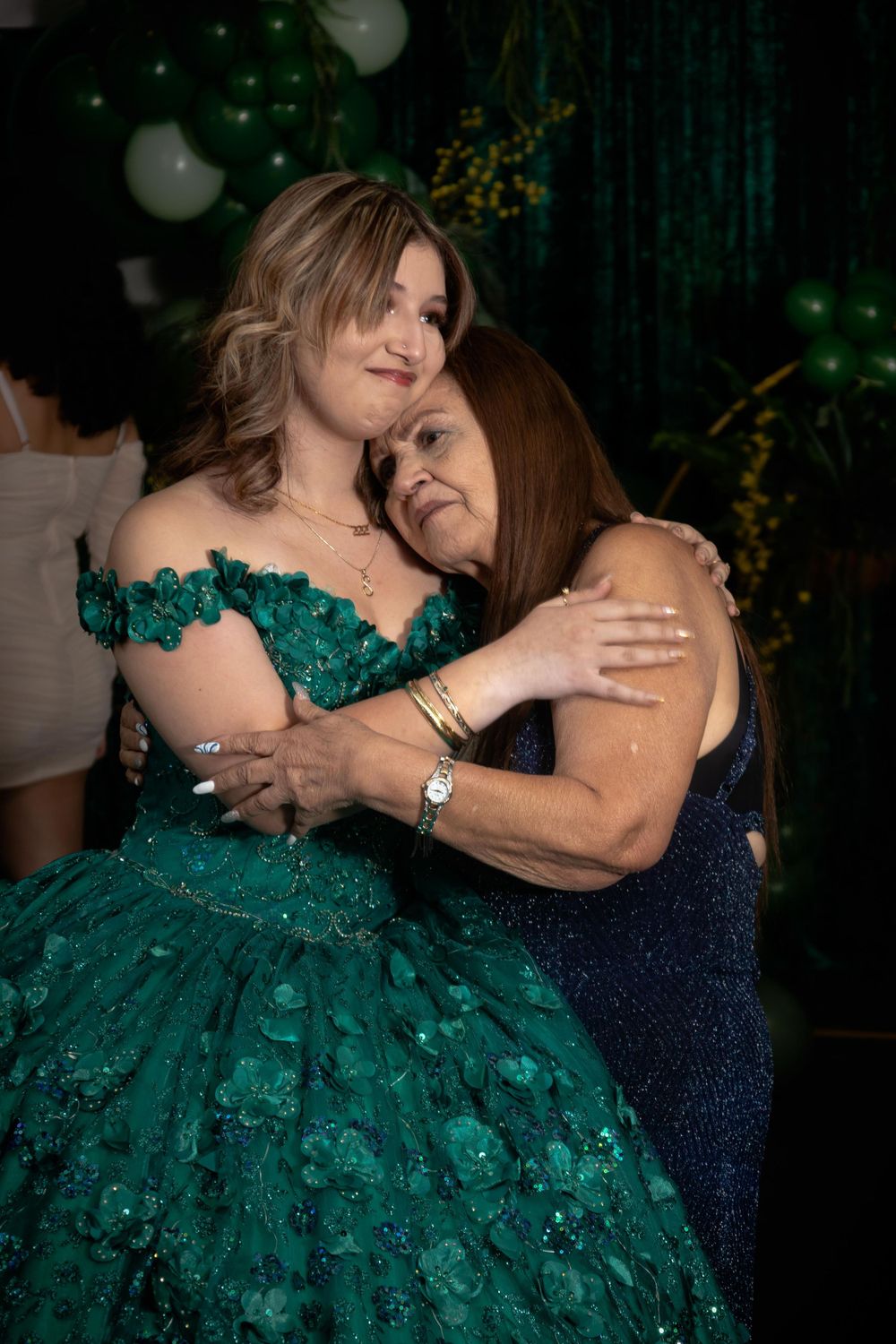 Tender embrace shared during formal celebration with emerald green gown and decorations.