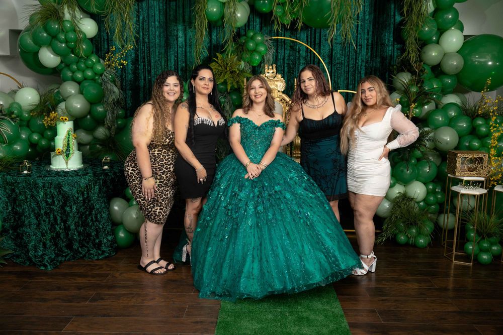 Festive gathering with emerald green decor, balloon arrangements, and formal attire.