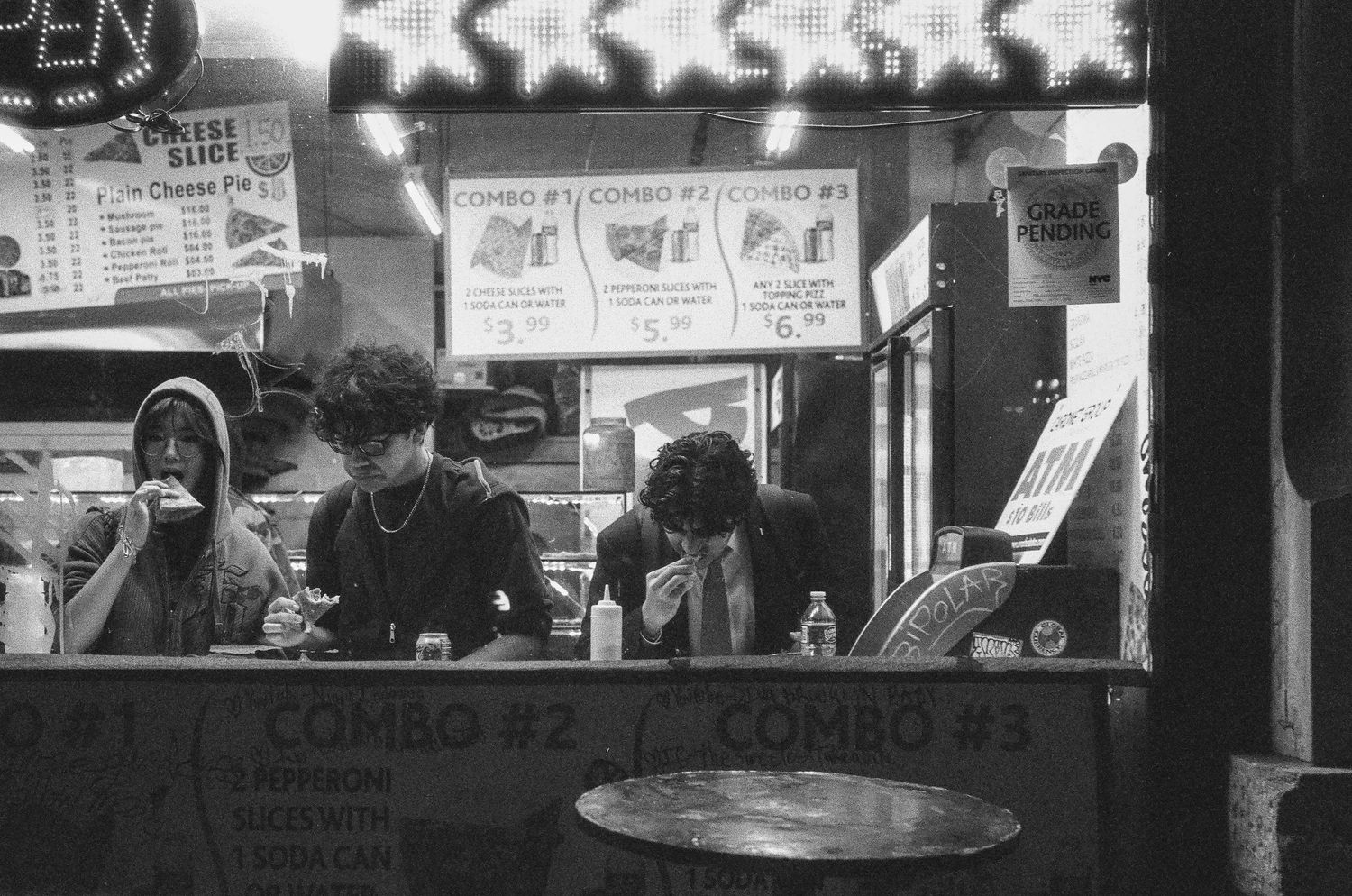 Dark nighttime view through a diner window showing silhouettes of customers at the counter.