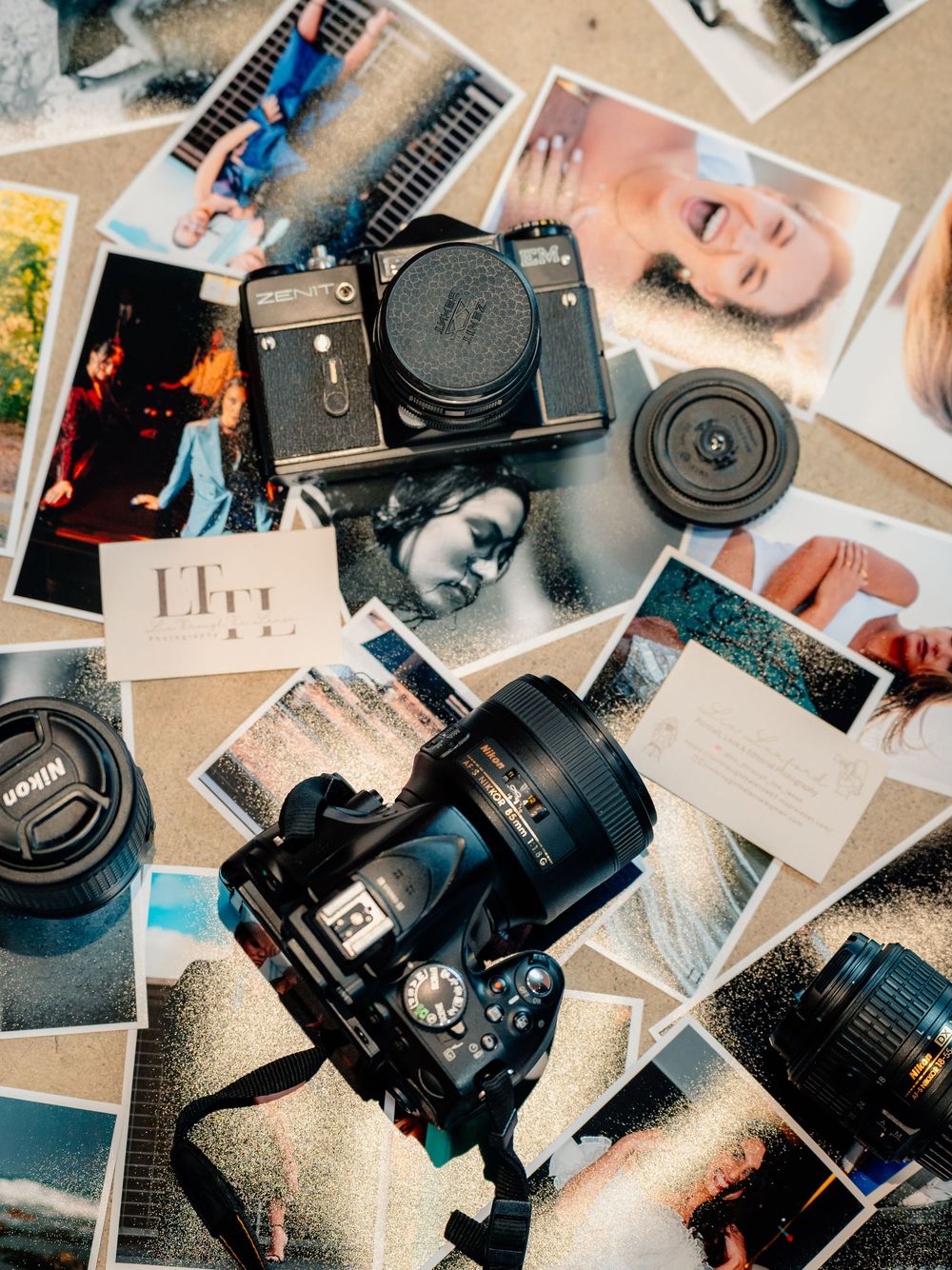 Vintage camera equipment and lenses scattered across printed photographs on a light surface.