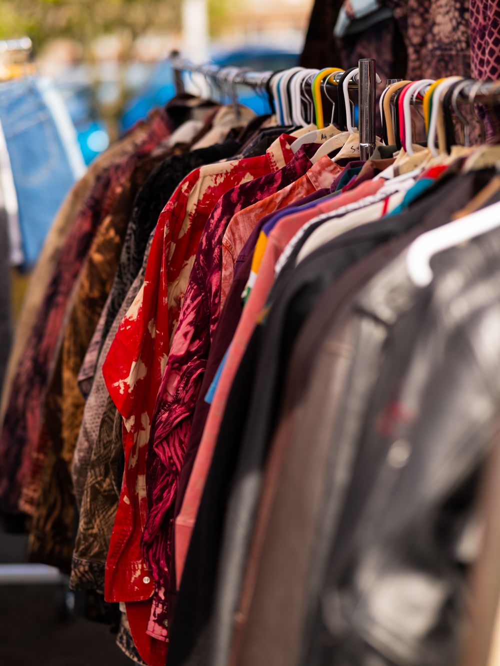 Colorful clothing on hangers displayed at a retail market or thrift store.