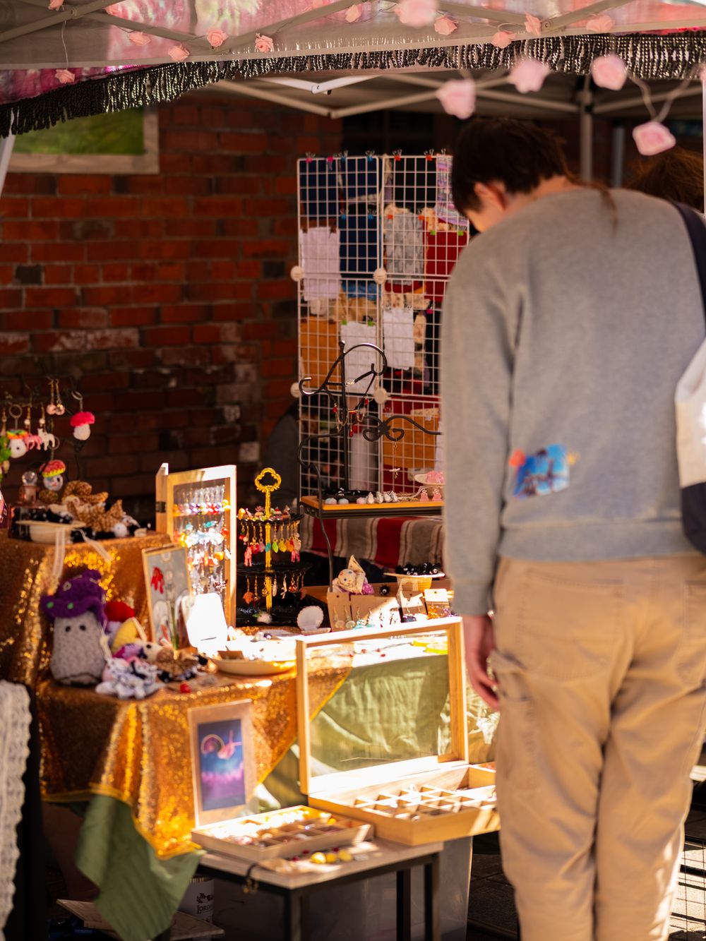 Market stall with wire display racks and string lights against brick wall.