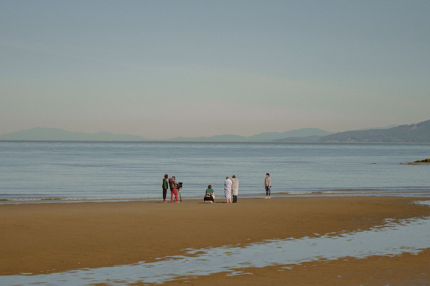Small group of people walking on a sandy beach during golden hour.
