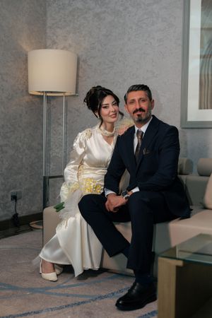 A couple sits together on a white couch in a modern gray room with table lamps and minimalist decor.