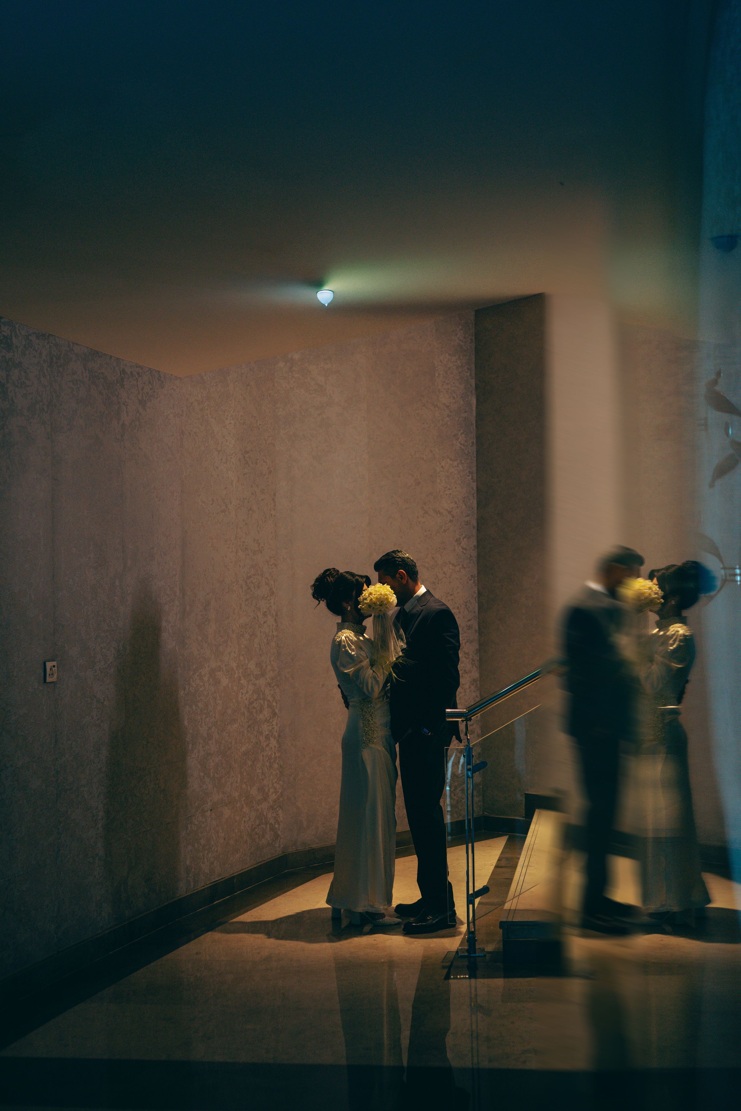 A romantic silhouette of a couple embracing in a dimly lit hallway with a mirror reflection creating a dreamy atmosphere.